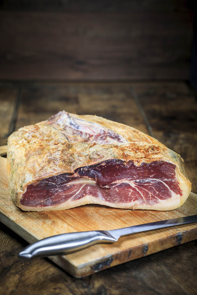 Demi jambon Serrano Gran Reserva avec os présenté sur planche en bois